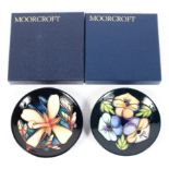 Two contemporary Moorcroft pin dishes, decorated with flowers on a blue ground,