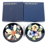 Two contemporary Moorcroft pin dishes, decorated with flowers on a blue ground,