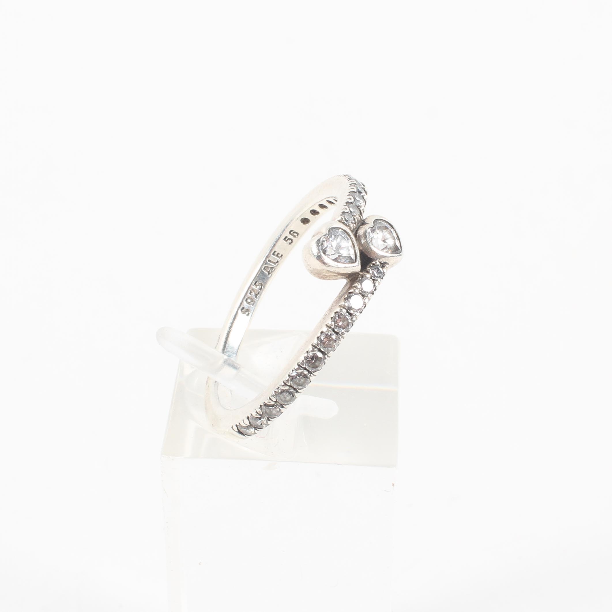 A sterling silver crossover ring set with heart and round cut colourless cubic zirconia.