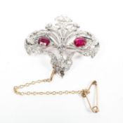 An unmarked white metal ruby and diamond brooch with two cushion cut rubies