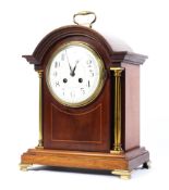An early 20th century inlaid mahogany mantel clock with gilt column supports and feet,