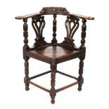 A Victorian carved oak corner chair, the foliate carved top rail with birds,