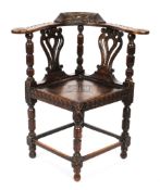 A Victorian carved oak corner chair, the foliate carved top rail with birds,