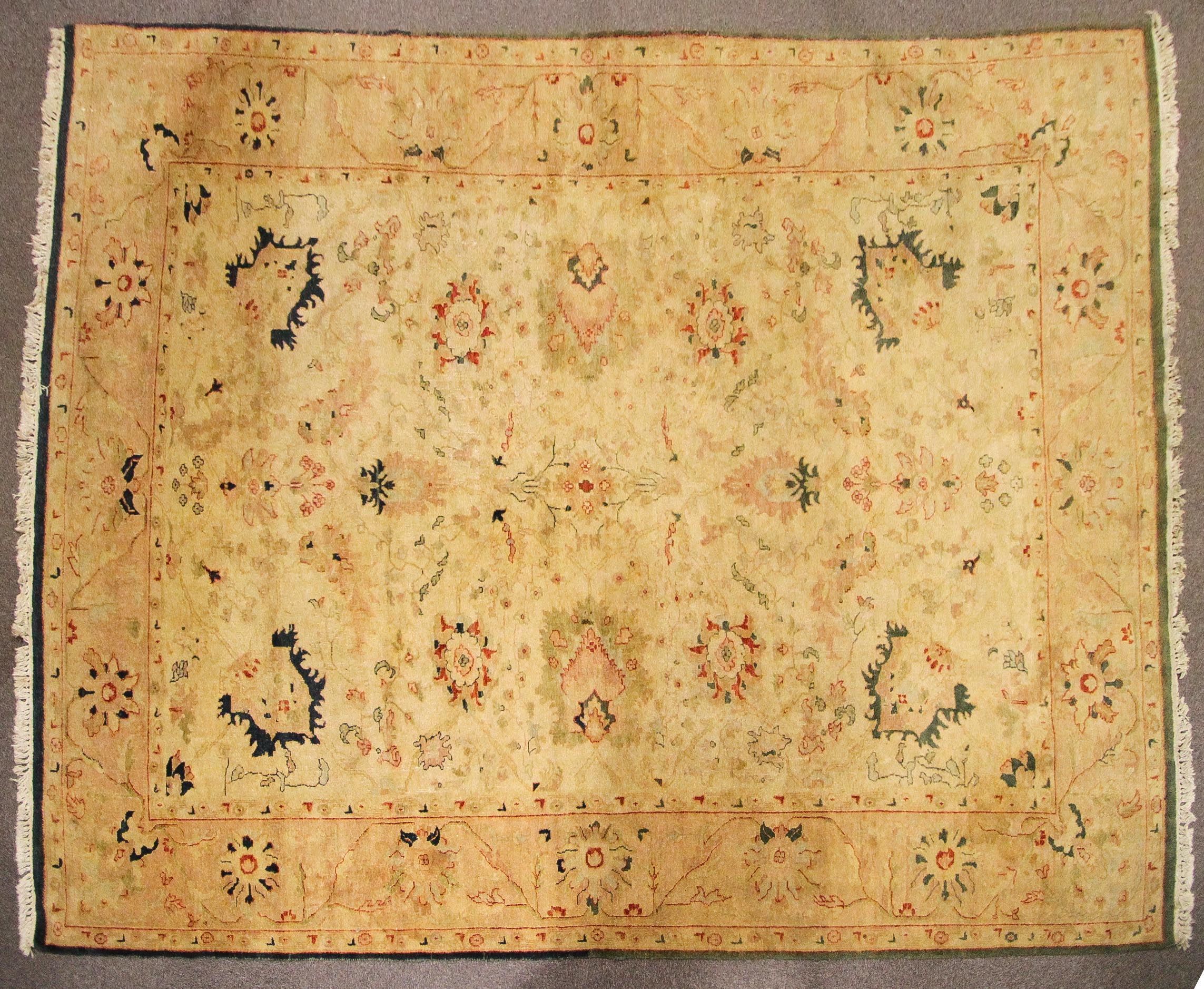 A Persian style large wool rug, woven with floral motifs on a buff/yellow ground,