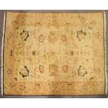 A Persian style large wool rug, woven with floral motifs on a buff/yellow ground,