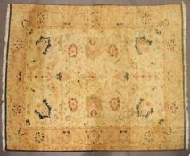 A Persian style large wool rug, woven with floral motifs on a buff/yellow ground,