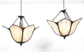 A pair of Edwardian petal shaped opaque pendant lights, each cast with beeded and floral frames,