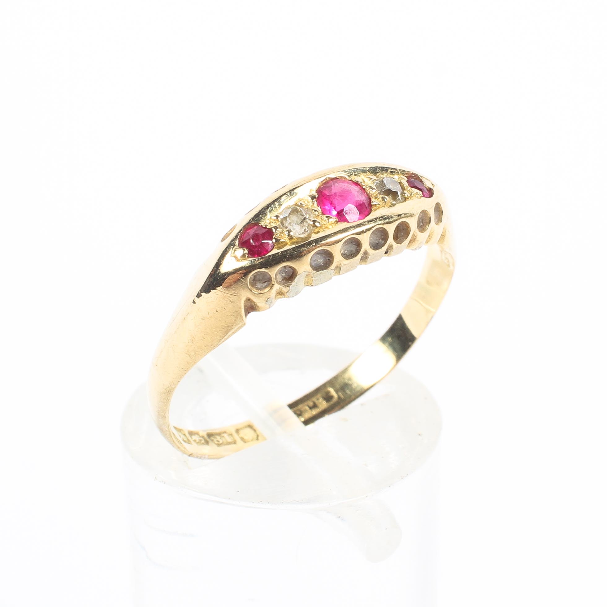 An 18ct gold ruby and diamond ring. Three round cut rubies with single cut diamond accents. 2.0g.