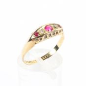 An 18ct gold ruby and diamond ring. Three round cut rubies with single cut diamond accents. 2.0g.