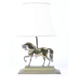 A brass lamp base cast as a horse on waisted plinth base, fitted for electricty, with cream shade,