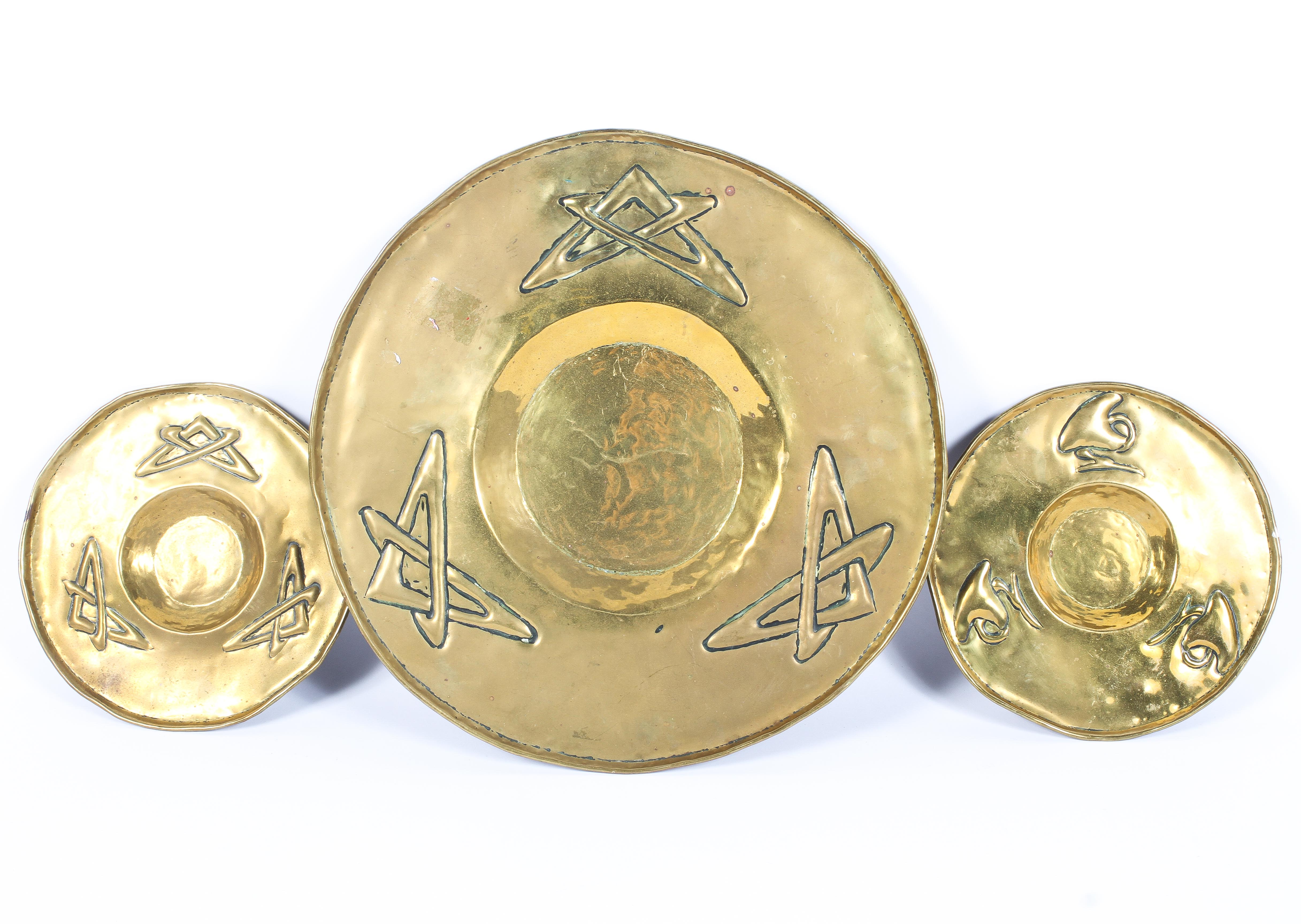Three brass Arts and Crafts style dishes, early 20th century, two small and one large,