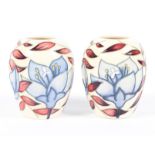 A pair of contemporary Moorcroft vases, each adorned with blue flowers amongst vines,