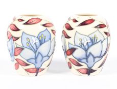A pair of contemporary Moorcroft vases, each adorned with blue flowers amongst vines,