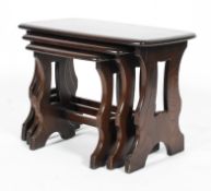 A nest of Ercol dark elm occasional tables, of shaped rectangular form, on pierced shaped supports,