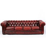 A large 20th Century Chesterfield sofa, with buttoned red leather upholstery, on wheels,