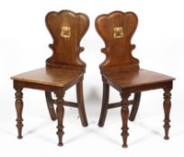 A pair of early Victorian mahogany armorial hall chairs,