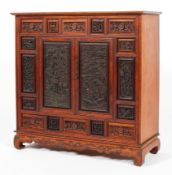 A Chinese carved hardwood cabinet, 20th century, the panelled front densely carved with dragons,