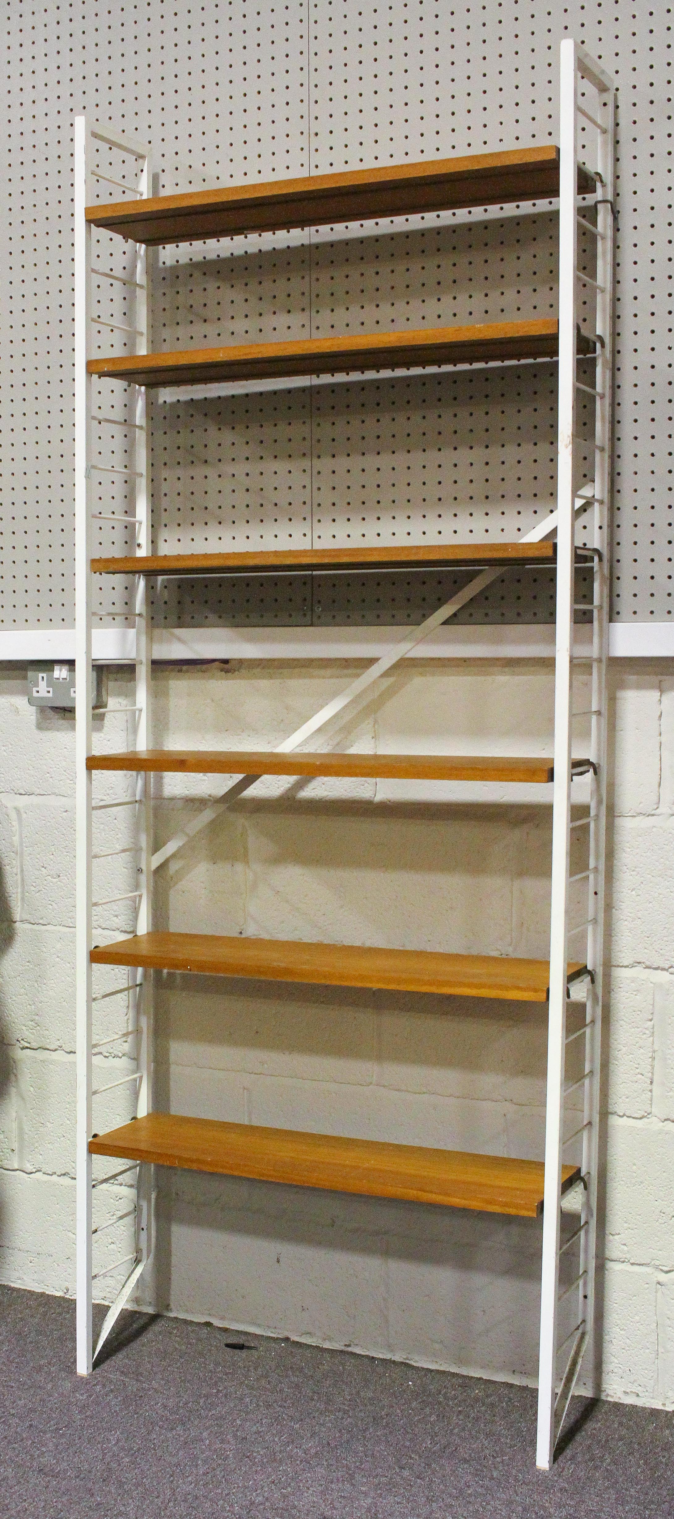 A set of Staples Ladderax shelving unit with white ladder supports and six teak shelves,