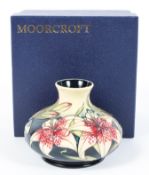 A contemporary Moorcroft vase, of circular squat form, depicting flowers on a blue ground,