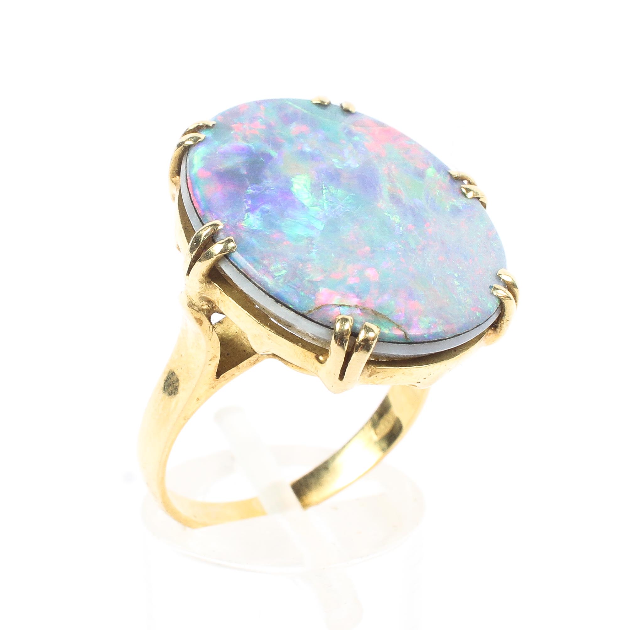 An 18ct gold 750 marked opal doublet ring. Central oval black opal panel in double six claw setting.