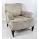 A 20th century armchair, with curved arms, raised on turned wooden supports,