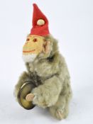 A 20th century clockwork toy of a clapping monkey wearing a red hat, height 22cm.