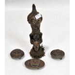 A carved wooden tribal figure together with three brass belt buckles