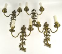 A set of four cast metal wall sconces, two branches, each supporting an artificial candle,