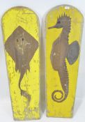 Two vintage wooden wake boards, with domed tops, decorated with sea creatures on a yellow ground,