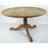 A circular pine tilt top table, on a turned pedestal base,