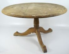 A circular pine tilt top table, on a turned pedestal base,
