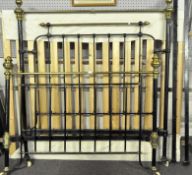 A cast iron double bed frame, glazed in black with brass details and finials, slacks present,