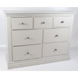 A contemporary grey chest of drawers with seven drawers and metal handles,