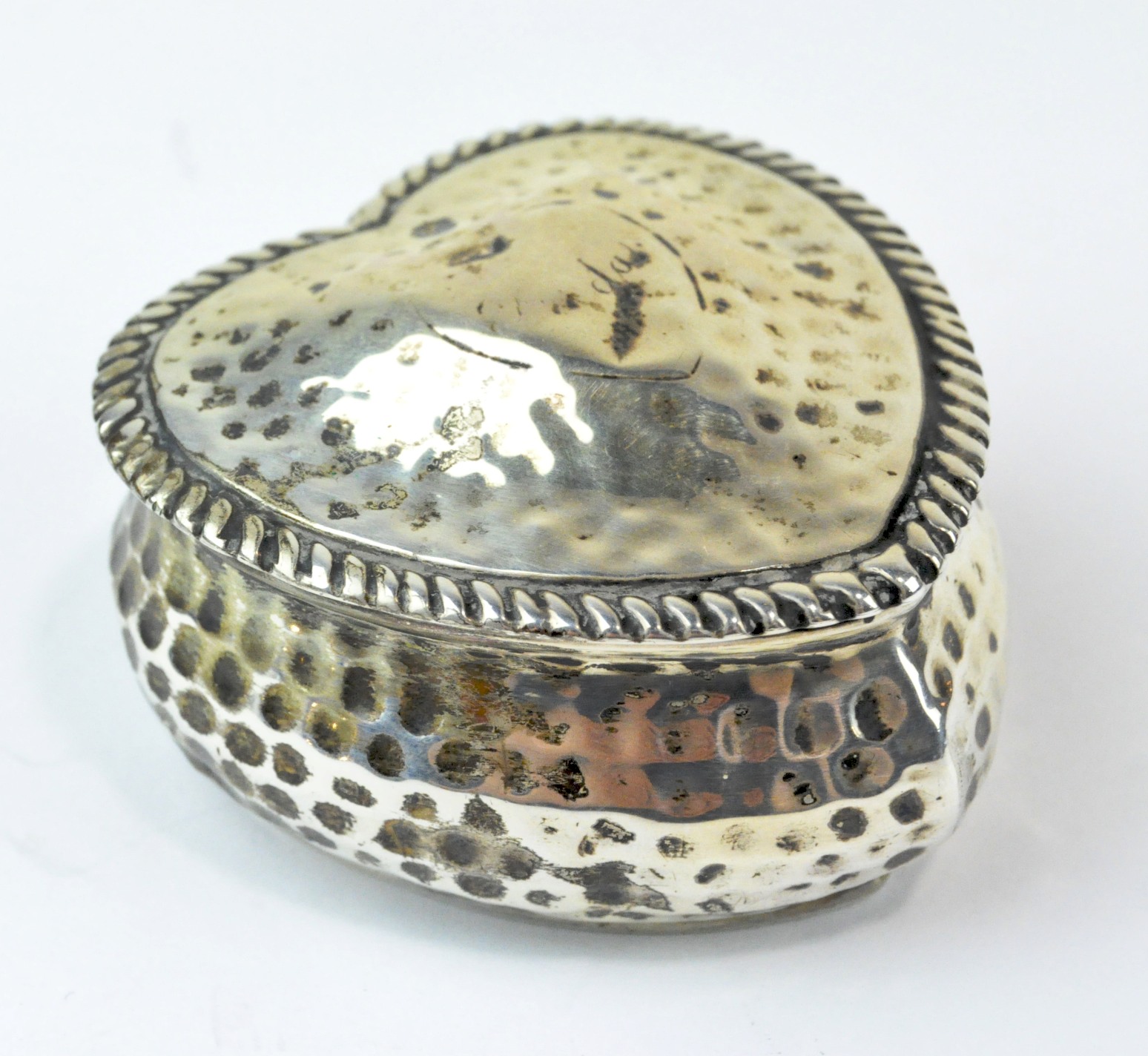 A late Victorian silver pill pot, of hammered, heart shaped form,
