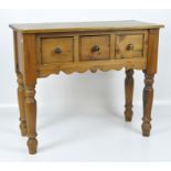 A 20th century pine side table, fitted with three drawers, raised on turned supports,