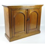 An Arts and Crafts hall cupboard, the two hinged doors decorated with shaped panels,
