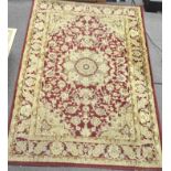 A 20th century Persian style rug, decorated with scrolling motifs and flowers on a red ground,