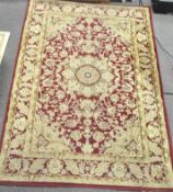 A 20th century Persian style rug, decorated with scrolling motifs and flowers on a red ground,