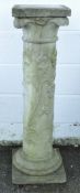 A reconstituted concrete garden column, decorated with flowers, circular base on raised plinth,