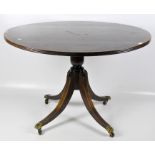 A mahogany breakfast table, with turned support and brass claw feet and castors,