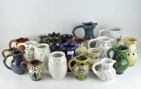 A collection of pottery puzzle jugs, in assorted glazes, some bearing sentences and words,