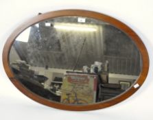 An oval wall mirror, with a wooden frame,