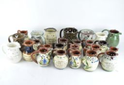 A collection of glazed puzzle pottery jugs, decorated in various colours,