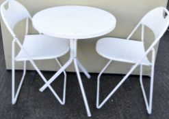 A contemporary metal garden table and two folding chairs, white painted,