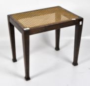 A 20th century oak stool with tapered supports and caned seat,