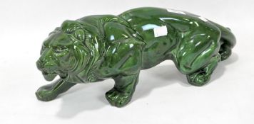 A ceramic model of a hunting lion, glazed in green, length 447cm.