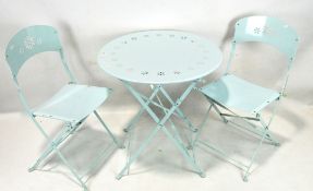 A contemporary blue metal folding circular table and two chairs, with pierced floral details,