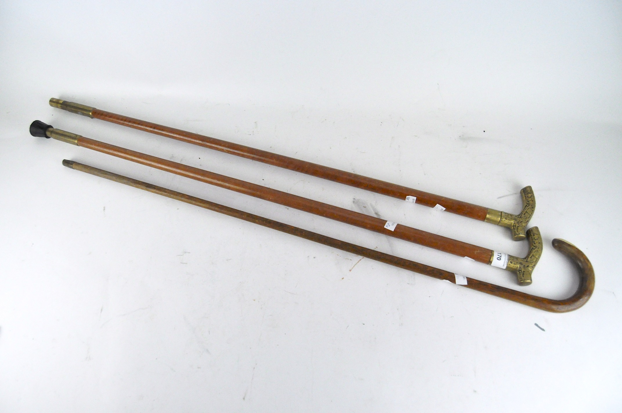 Three walking canes, all wooden sticks, one with a curved handle,