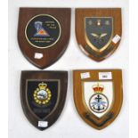 A group of four armorial wall plaques, each mounted to wooden shields,