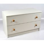 A contemporary chest of drawers, two drawers with turned pine handles, painted white,